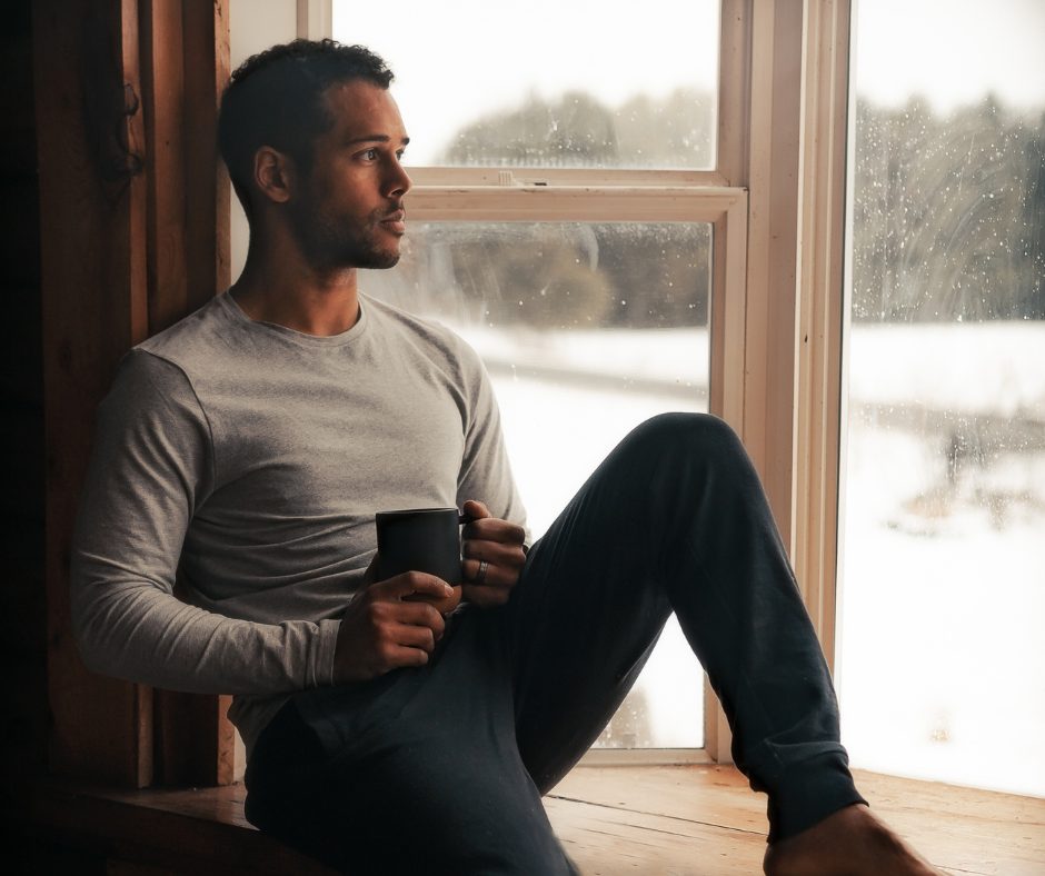 Man looking out a window reflecting - representing trauma, PTSD, and the need for counselling support