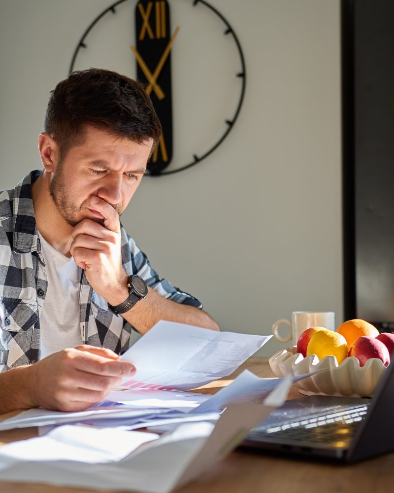 Man at desk surrounded by papers looking stressed and overwhelmed — representing the disorganization and mental load many men with undiagnosed ADHD carry daily