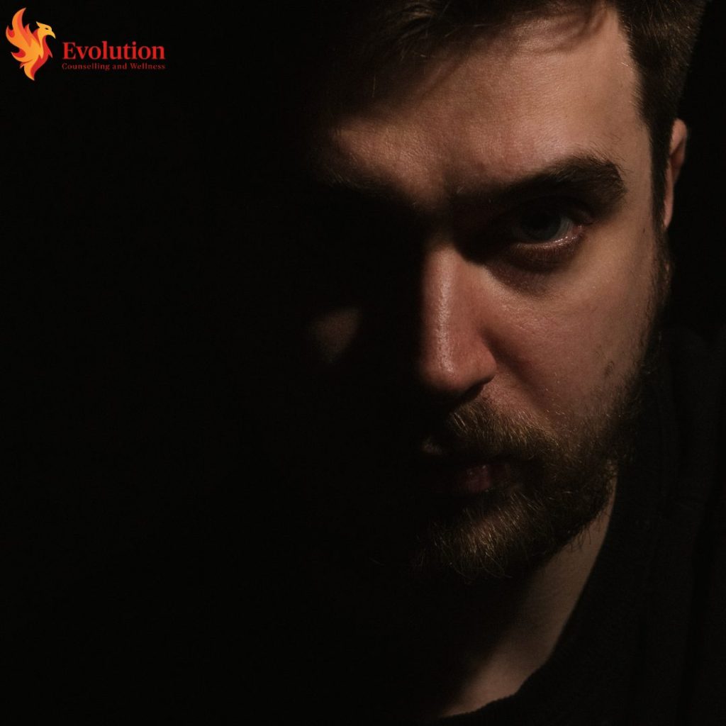 Close-up portrait of a man with a beard, half in shadow against a dark background; Evolution Counseling and Wellness logo in the top-left.